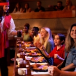 A waitress dressed in pirate garb serves food to excited onlookers at the Pirates Voyage Dinner & Show in Myrtle Beach.