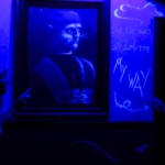 A blue-lit room with two people pointing at a mysterious portrait at Ripley's Haunted Adventure at Myrtle Beach.