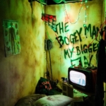 An eerie room with a tv turned on the news and words scribbled on the wall at Ripley's Haunted Adventure at Myrtle Beach.