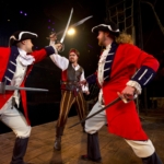 A pirate fights off two members of a navy at a Pirates dinner & show in myrtle beach