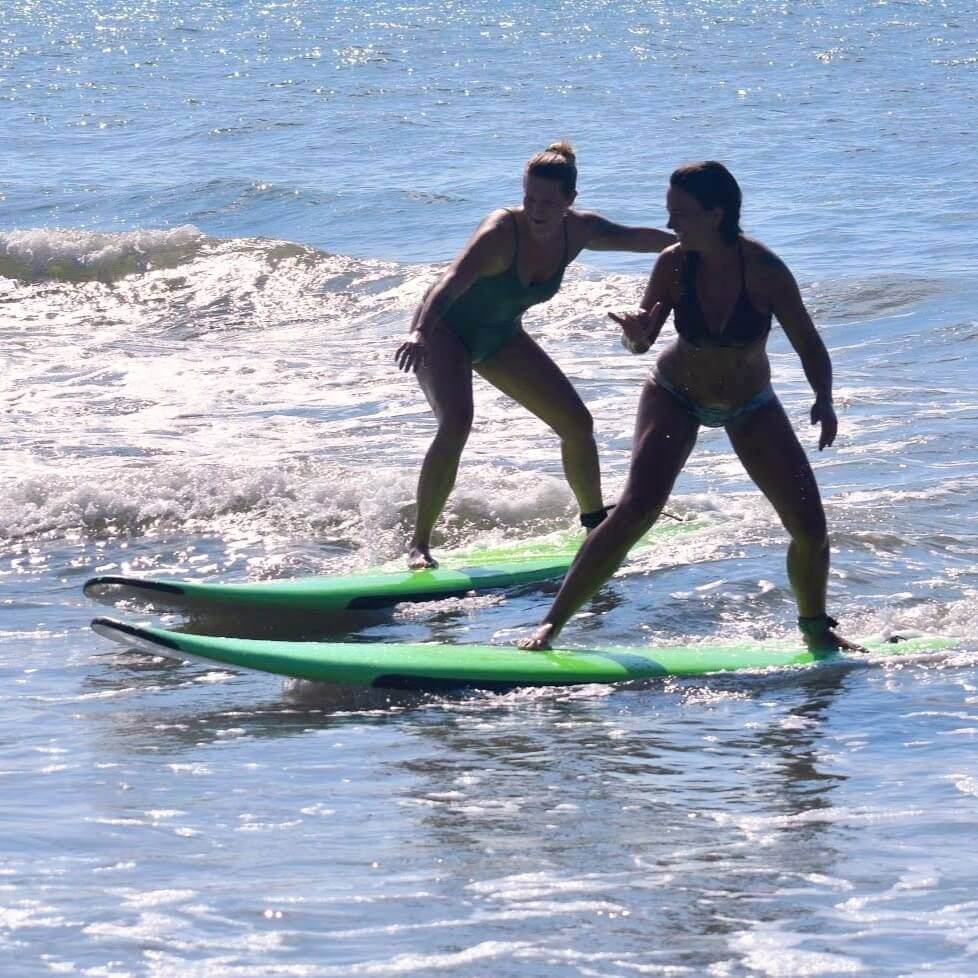 Two women learning to surf with Kokopelli Surf Camp instructors in Myrtle Beach