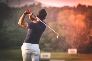 Golfer finishing his swing as dirt and grass fly