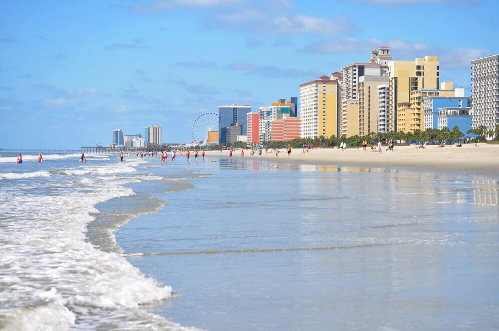 A scenic view of Myrtle Beach with rolling waves and distant buildings in the background.