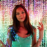 A woman standing in front of a wall of string lights.