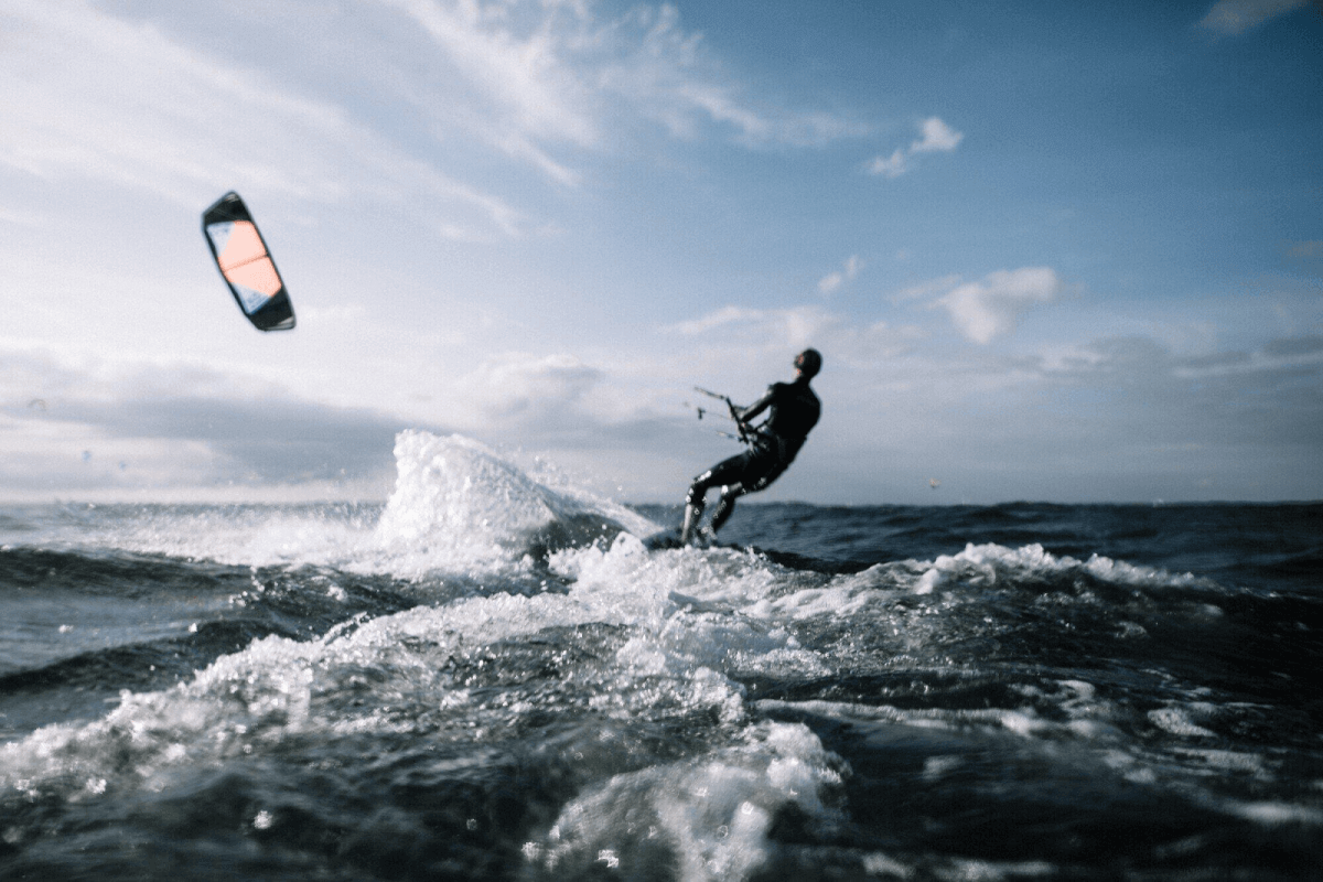 A man kiteboarding in the ocean on a sunny day.