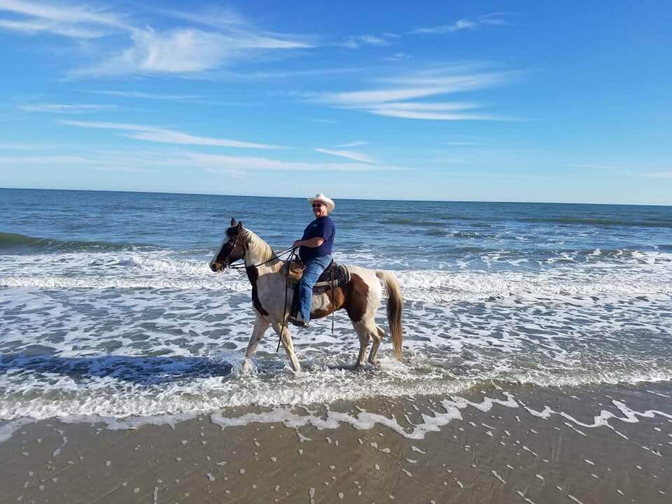 Horseback rider walking through shallow waves during a Myrtle Beach beach ride