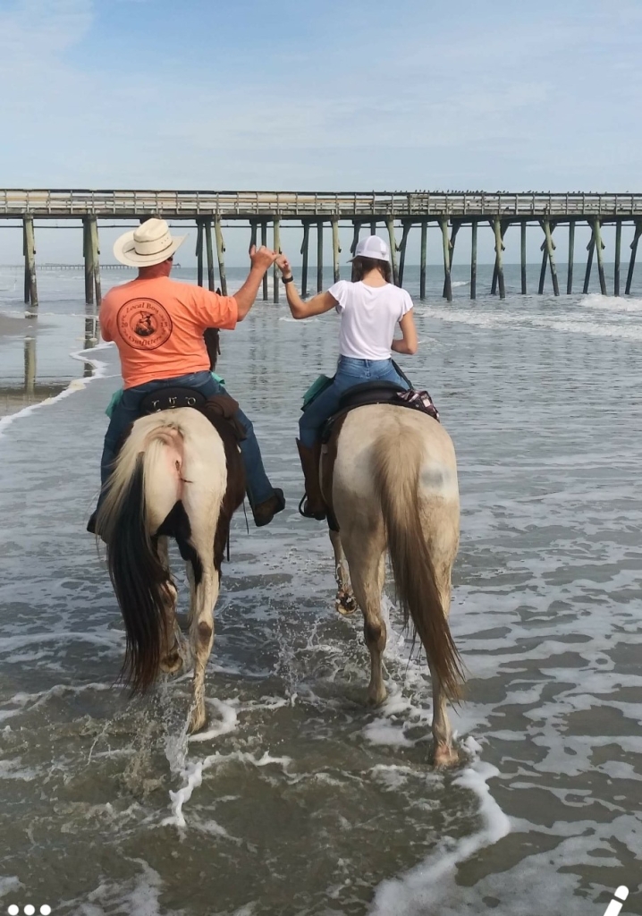 Sunset horseback riding near a Myrtle Beach pier during the off-season