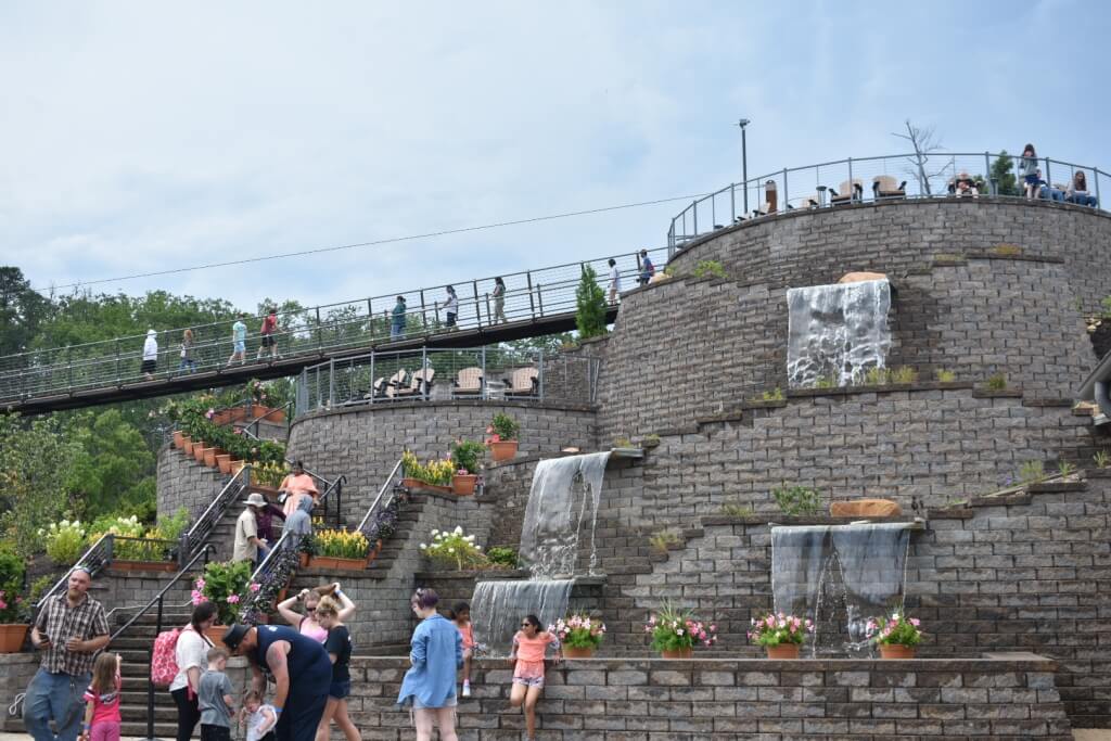 Visitors walking across the Gatlinburg SkyBridge at SkyPark with tiered waterfalls and mountain views.