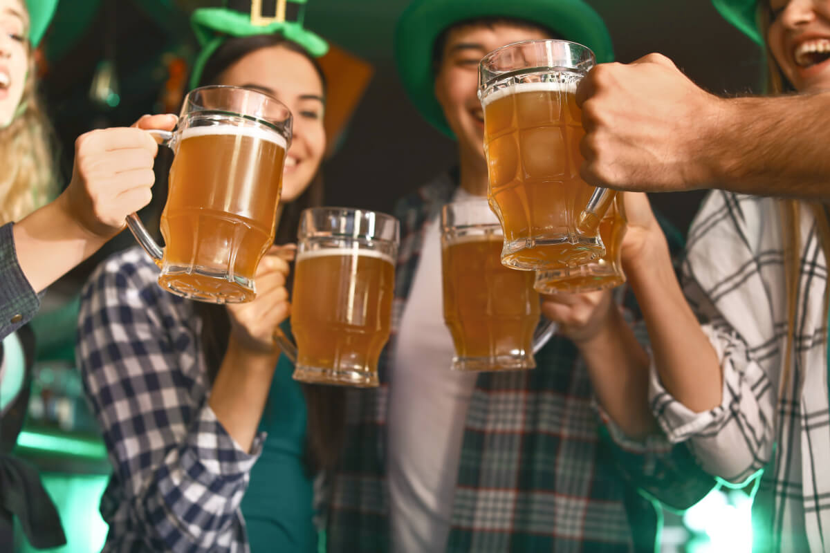 Young friends with beer celebrating St. Patrick's Day in pub