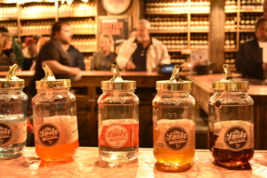 Ole Smoky moonshine tasting jars lined up at The Holler in Gatlinburg with visitors in the background