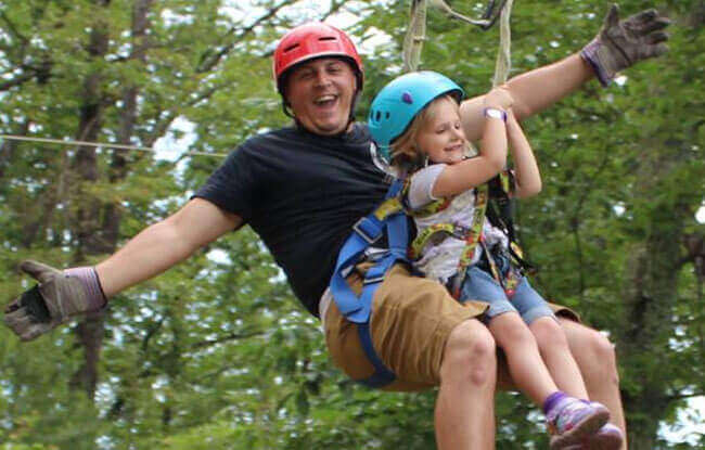 Dad and young daughter tandem ziplining at Legacy Mountain in Gatlinburg, Tennessee.