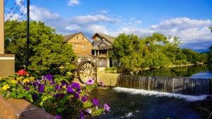 The Old Mill in Pigeon Forge with a historic waterwheel and flowers along the Little Pigeon River.