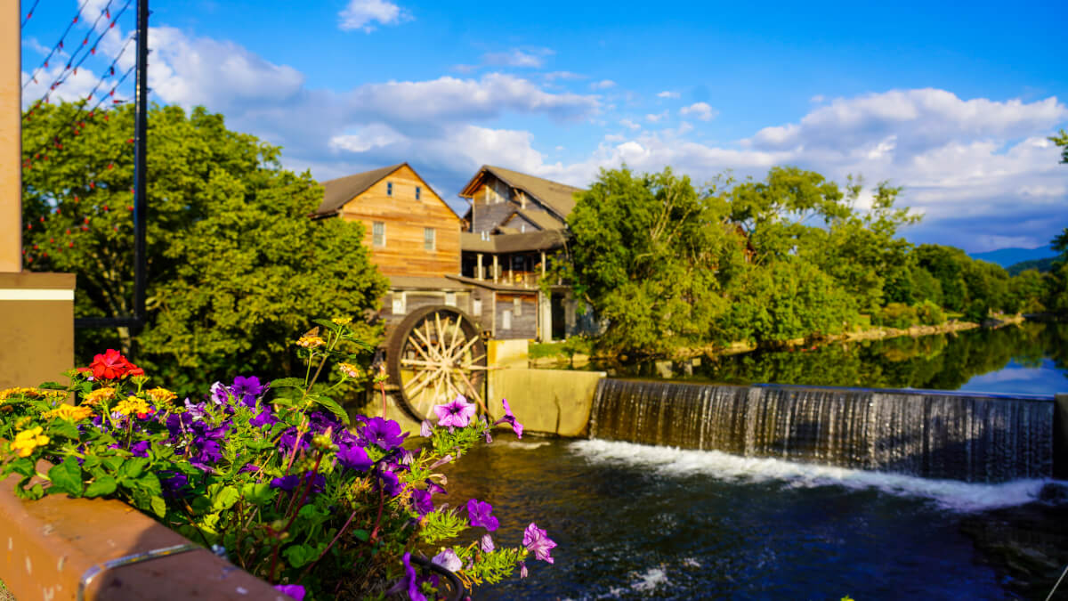 The Old Mill in Pigeon Forge with a historic waterwheel and flowers along the Little Pigeon River.