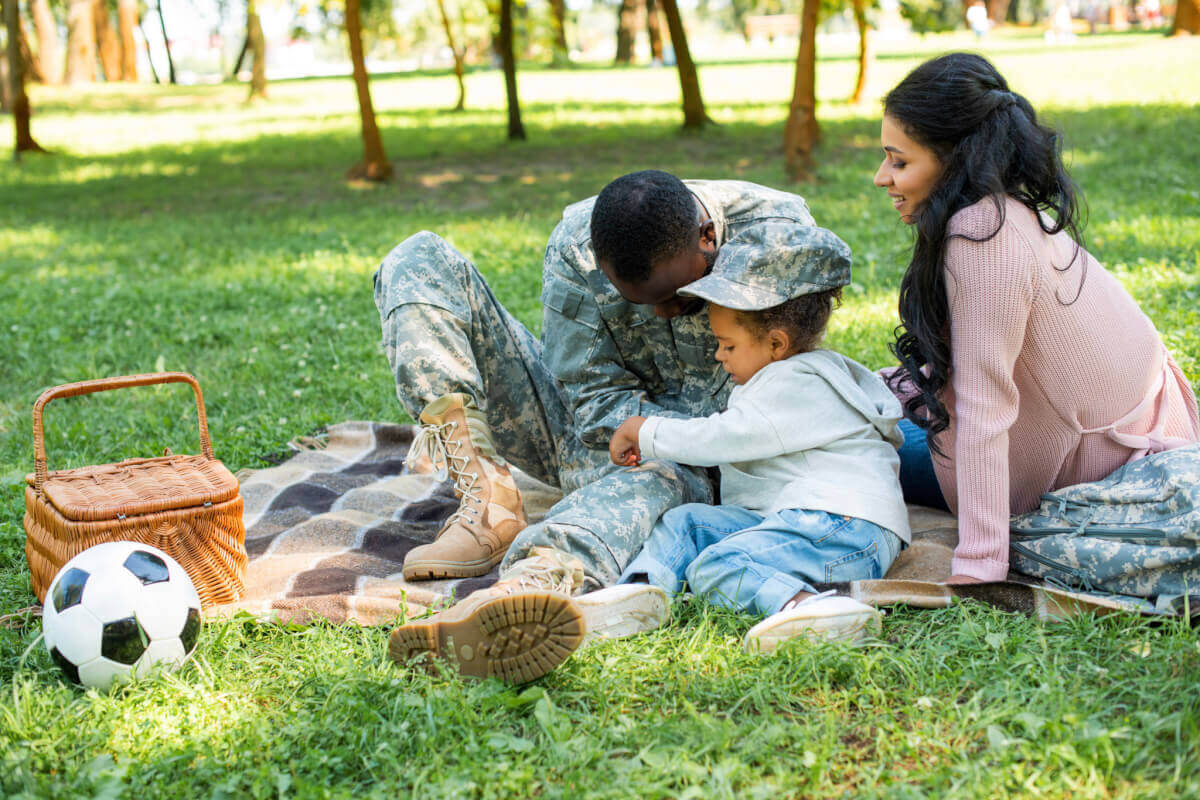 Picnic at Patriot Park in Pigeon Forge with a family sitting on a blanket in the grass near a picnic basket and soccer ball.