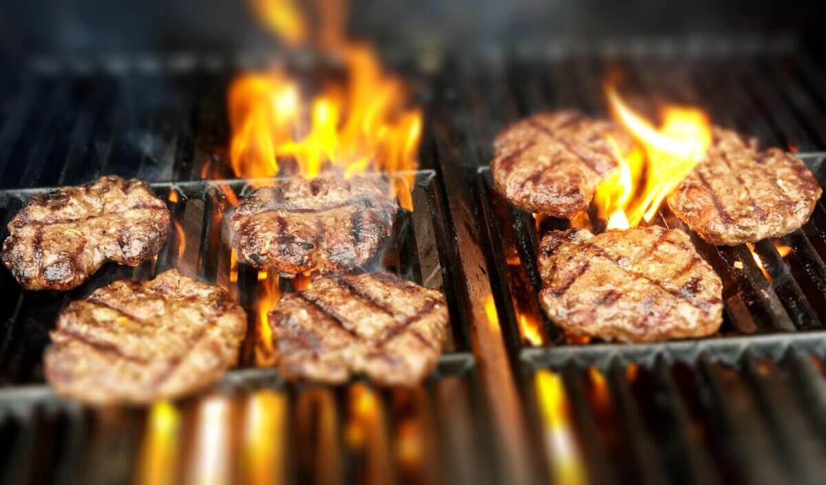 Steaks sizzling on a hot grill, smoke rising, creating a mouthwatering aroma.