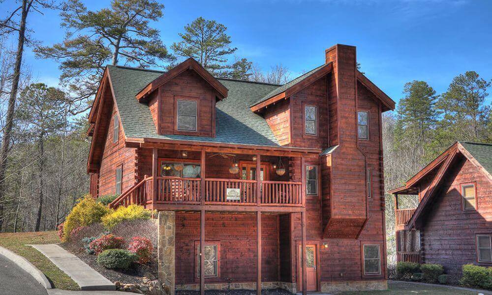 A cozy log cabin with a charming porch and balcony, nestled in nature's embrace.