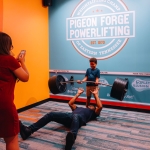 A family pose a picture making it seem like the child is lifting a lot of weight.